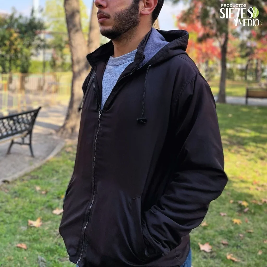 Hombre con chaqueta negra con capucha en un parque